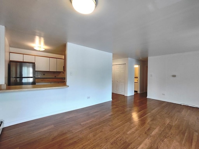 unfurnished living room with wood finished floors and baseboards