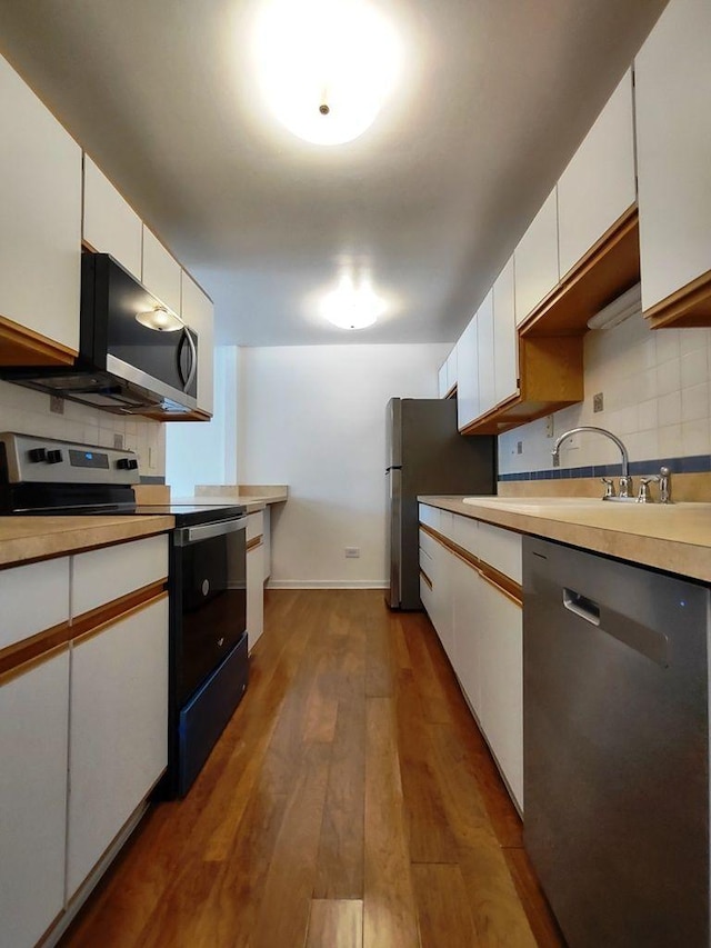 kitchen featuring stainless steel appliances, a sink, decorative backsplash, and white cabinets