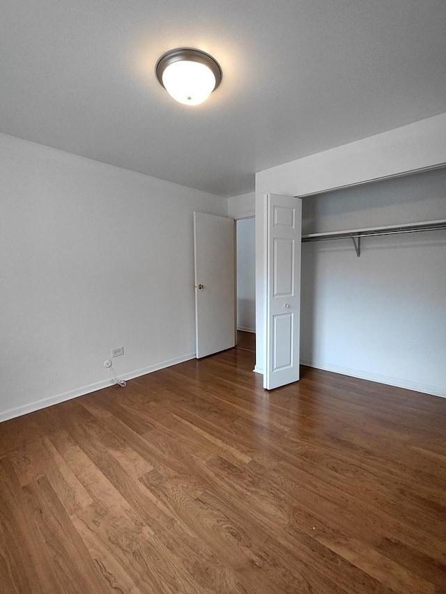 unfurnished bedroom with wood finished floors, a closet, and baseboards