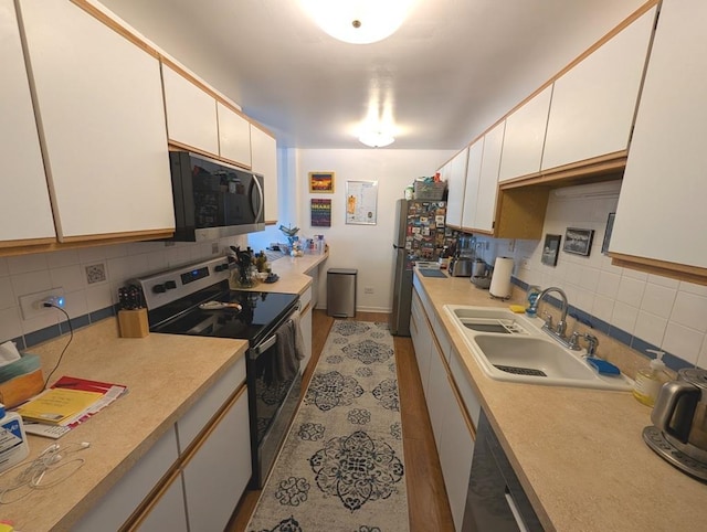 kitchen with appliances with stainless steel finishes, backsplash, a sink, and light countertops