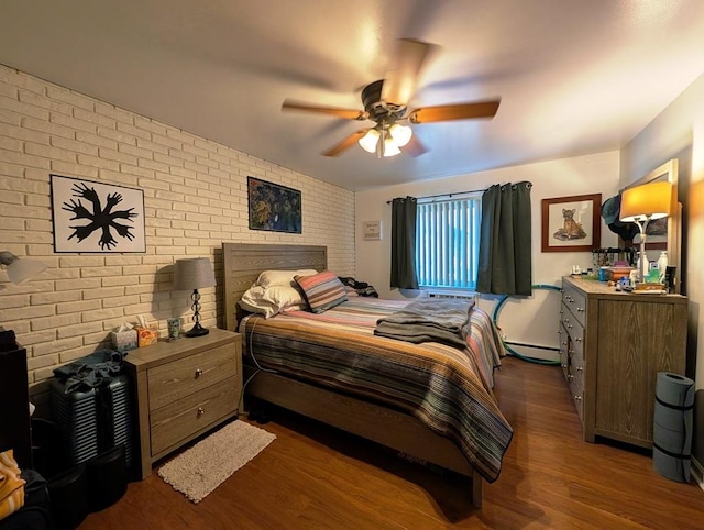 bedroom featuring brick wall, wood finished floors, baseboard heating, and a ceiling fan