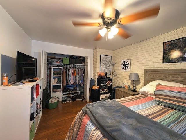 bedroom with wood finished floors, brick wall, a closet, and a ceiling fan
