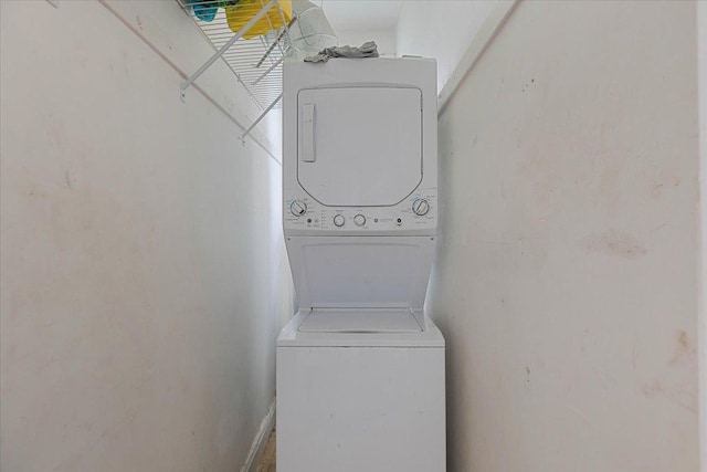 clothes washing area featuring stacked washer and dryer and laundry area