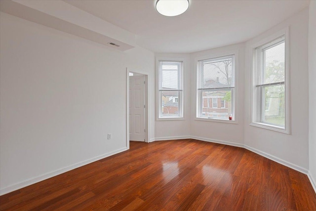 spare room featuring dark wood-type flooring, baseboards, and visible vents