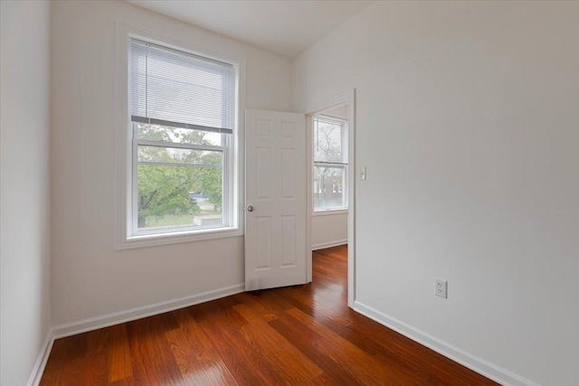 empty room with baseboards and dark wood-type flooring