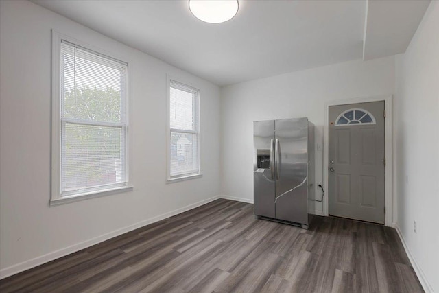 interior space featuring baseboards, stainless steel fridge with ice dispenser, and dark wood-type flooring