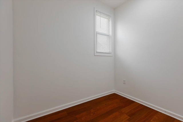spare room featuring dark wood finished floors and baseboards