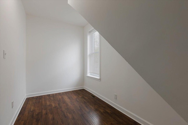 additional living space with baseboards, dark wood-style flooring, and visible vents