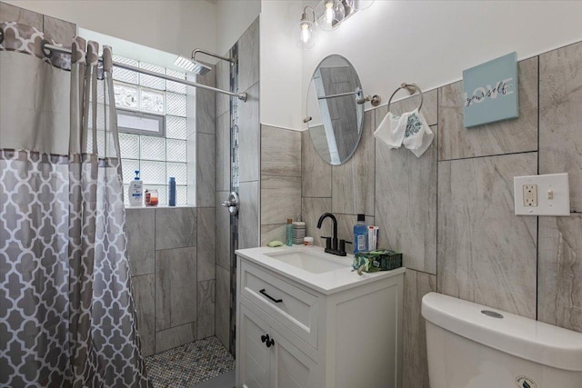 full bath with tile walls, toilet, a tile shower, and vanity