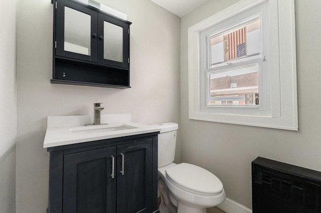half bath with toilet, vanity, and baseboards