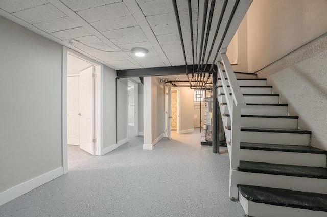 finished below grade area with gas water heater, baseboards, and stairs