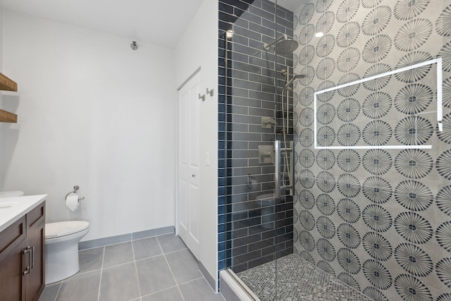 full bath with tile patterned flooring, a tile shower, vanity, baseboards, and toilet