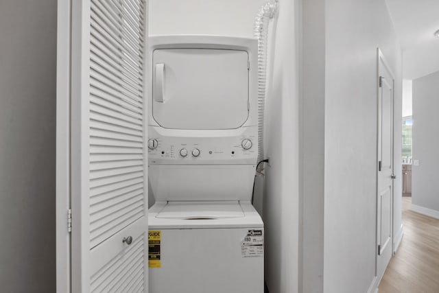 laundry room with stacked washer / drying machine, light wood-style flooring, and laundry area