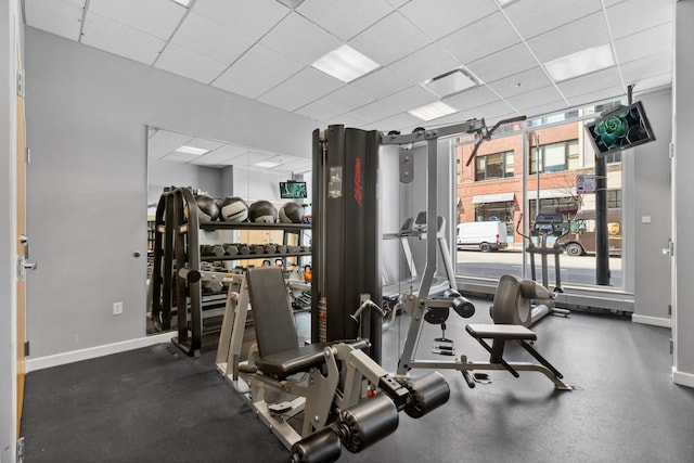 gym featuring baseboards and a paneled ceiling