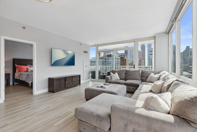living area featuring plenty of natural light, light wood finished floors, and a wall of windows