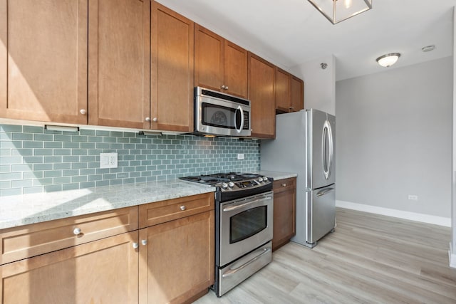 kitchen featuring light wood-type flooring, decorative backsplash, baseboards, and stainless steel appliances