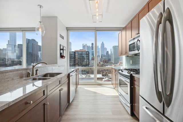 kitchen featuring visible vents, a view of city, a sink, light wood-style flooring, and appliances with stainless steel finishes