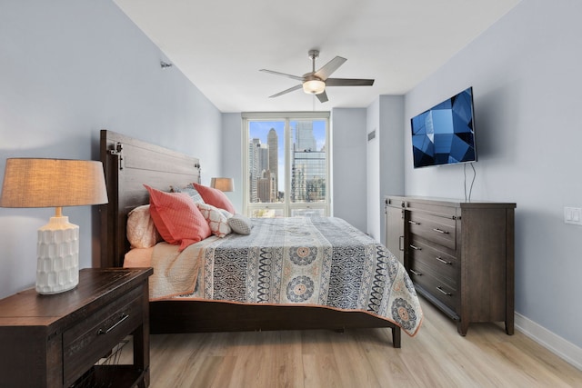 bedroom featuring light wood-style floors, a ceiling fan, and baseboards