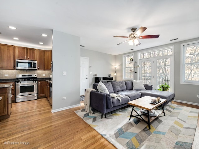 living room featuring light wood-style floors, baseboards, a ceiling fan, and recessed lighting