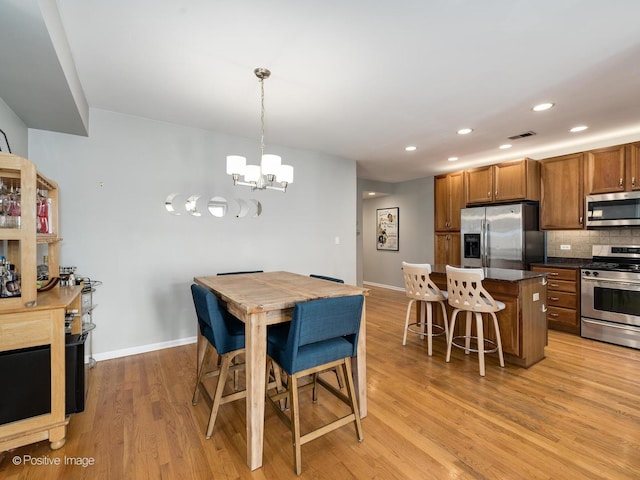 dining space featuring light wood finished floors, a chandelier, baseboards, and recessed lighting