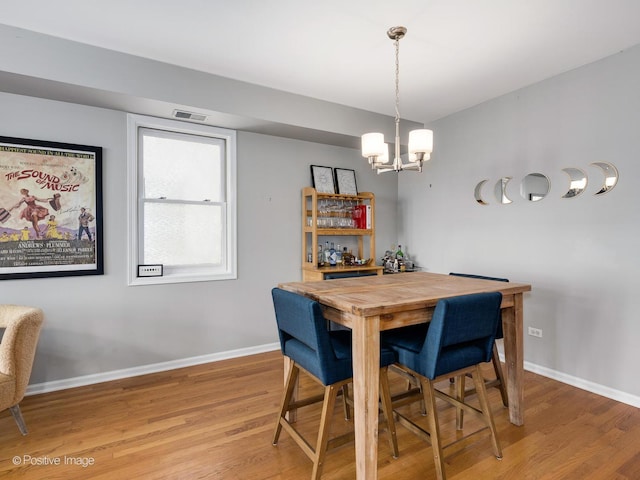 dining area featuring light wood-style flooring, baseboards, and a chandelier