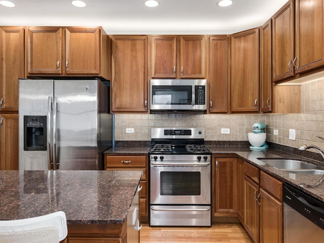 kitchen with stainless steel appliances, a sink, brown cabinetry, and recessed lighting