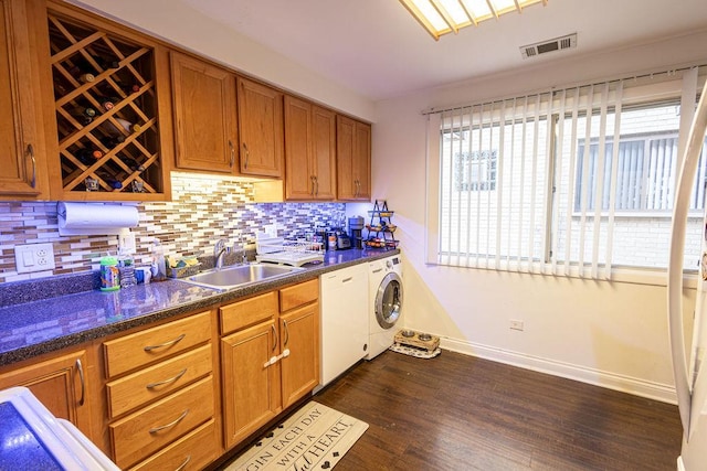 kitchen with backsplash, washing machine and clothes dryer, visible vents, dishwasher, and a sink