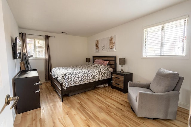 bedroom featuring a fireplace, light wood finished floors, and visible vents