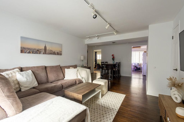 living room featuring track lighting, baseboards, and dark wood-type flooring