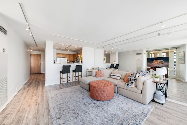 living area featuring track lighting, light wood-style floors, and baseboards