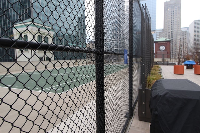 view of tennis court featuring fence and a city view