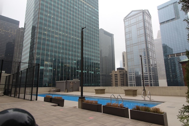 community pool featuring fence, a city view, and a patio