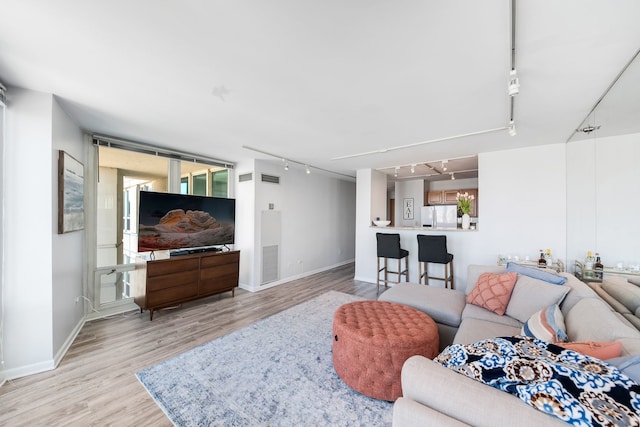 living area with baseboards, rail lighting, light wood finished floors, and visible vents