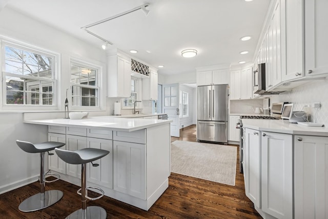 kitchen featuring light countertops, stainless steel appliances, white cabinetry, and a peninsula