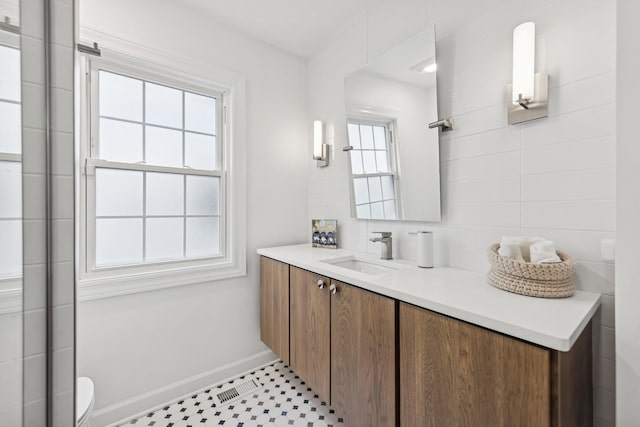 full bath featuring baseboards, a shower with shower door, toilet, and vanity