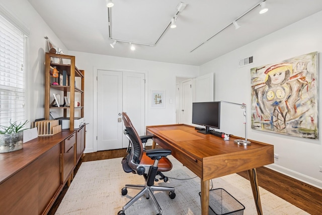 office featuring track lighting, attic access, dark wood-style floors, and visible vents