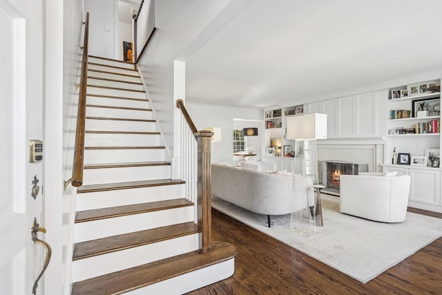 interior space with stairs, a glass covered fireplace, and dark wood-style floors