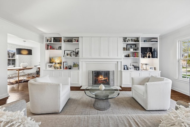 living room featuring a glass covered fireplace, ornamental molding, and wood finished floors