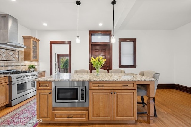 1625 Central Ave, Wilmette, IL 60091 - kitchen featuring a kitchen breakfast bar, wall chimney range hood, light wood-type flooring, tasteful backsplash, and appliances with stainless steel finishes