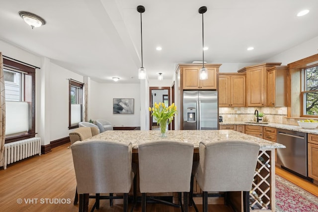 1625 Central Ave, Wilmette, IL 60091 - kitchen featuring a center island, a sink, radiator heating unit, a breakfast bar, and stainless steel appliances