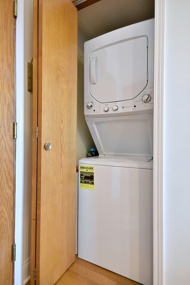 laundry area with laundry area, stacked washing maching and dryer, and wood finished floors