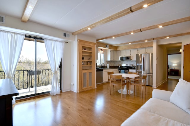 living room featuring light wood-style floors, baseboards, beam ceiling, and visible vents