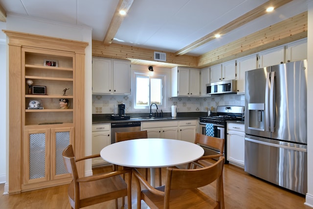 kitchen with a sink, dark countertops, stainless steel appliances, and visible vents