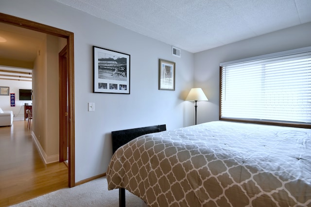 bedroom featuring baseboards, a textured ceiling, and visible vents