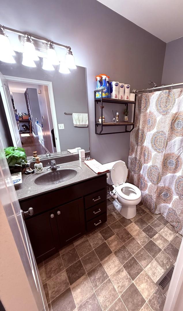 10817 Quail Xing, Richmond, IL 60071 - bathroom with stone finish floor, a shower with curtain, visible vents, toilet, and vanity