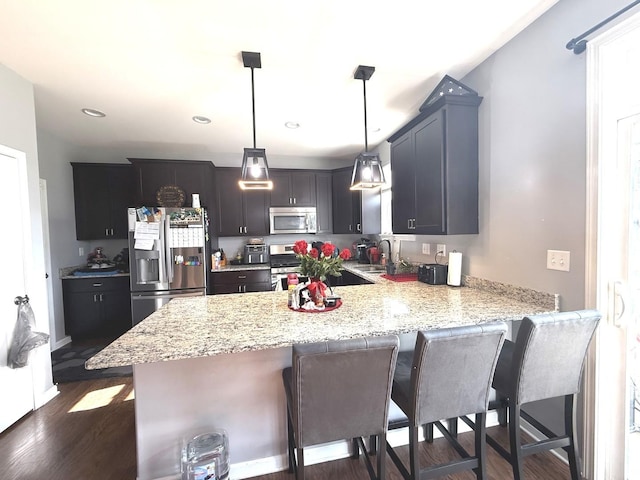 10817 Quail Xing, Richmond, IL 60071 - kitchen featuring a breakfast bar area, a sink, stainless steel appliances, light stone countertops, and a peninsula