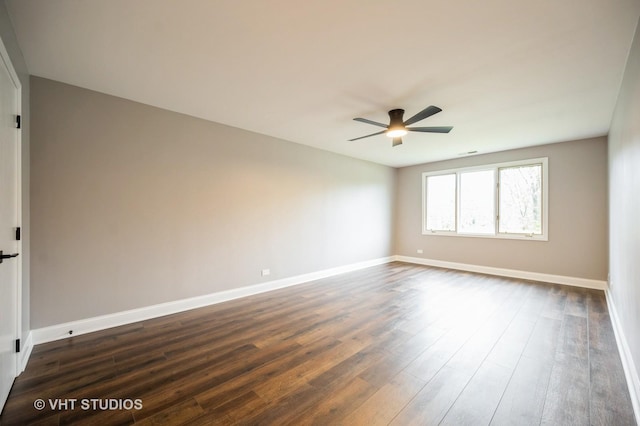spare room with baseboards, dark wood-style flooring, and ceiling fan