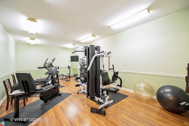 exercise area with baseboards and wood finished floors