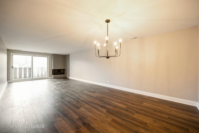 interior space with an inviting chandelier, a large fireplace, baseboards, visible vents, and dark wood-style floors