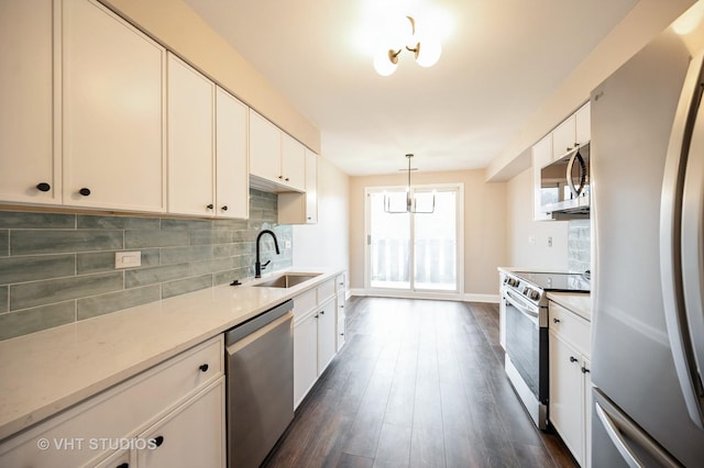 kitchen featuring a sink, dark wood finished floors, backsplash, hanging light fixtures, and stainless steel appliances